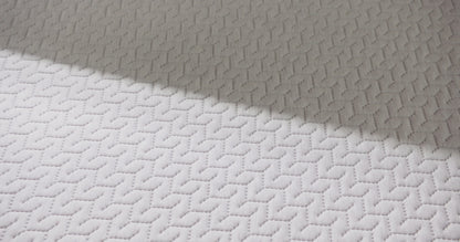 Woman presses hand on hybrid mattress.