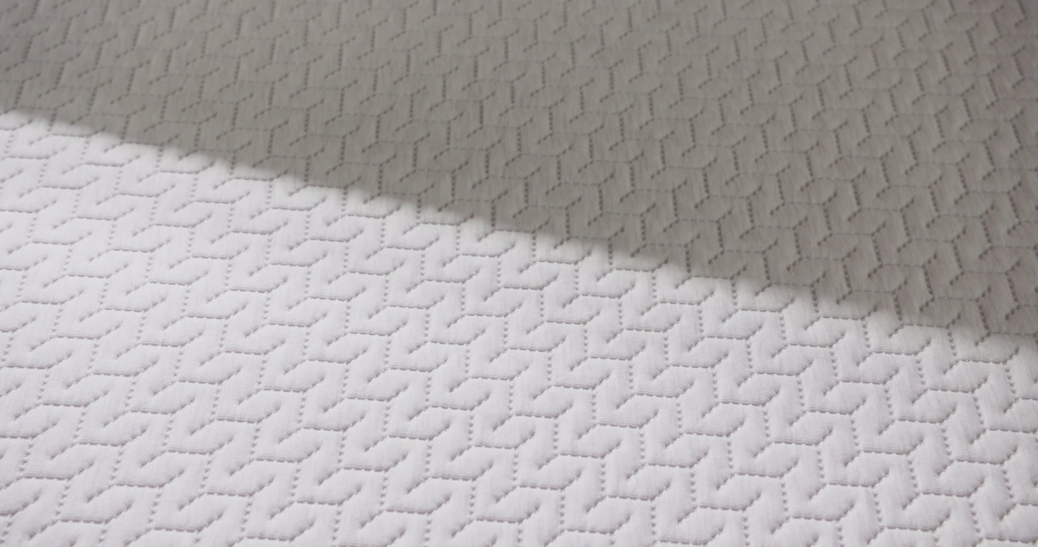 Woman presses hand on hybrid mattress.