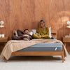 A couple laying on the Tuft and Needle Bestselling T&N Mint Mattress in a bedroom