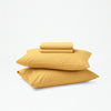 The Tuft and Needle Organic Percale Sheet Set folded and stacked on 2 pillows||color:Butternut